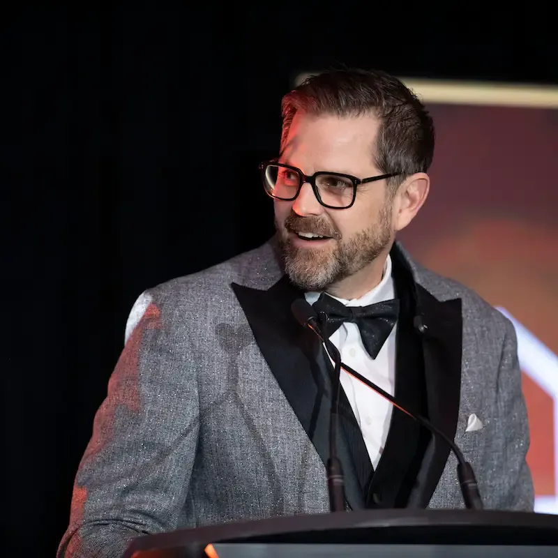 Cliff looking at the audience as he is up at a podium