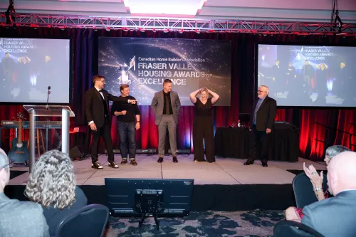 Individuals on stage playing games as Cliff hosts the CHBA Fraser Valley Housing Awards of Excellence.