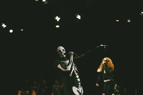 an individual in a skeleton costume holding a mic along with Tia the officiant
