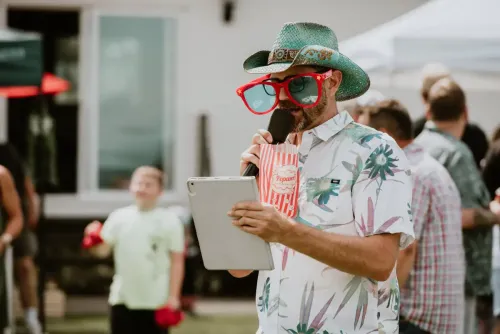 Cliff emceeing for LEAP event with oversized clown glasses and a teal cowboy hat