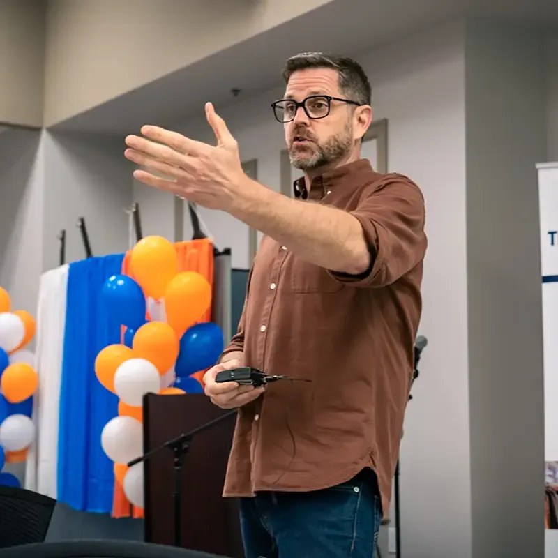 Cliff speaking to a crowd with arm extended