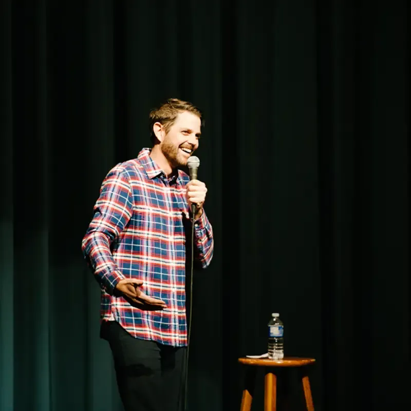 Cliff with a mic in hand at a stand-up comedy show